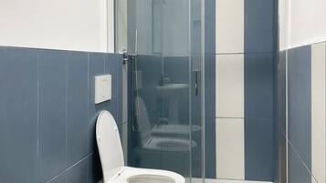 Et badeværelse med brusekabine, toilet og håndvask.