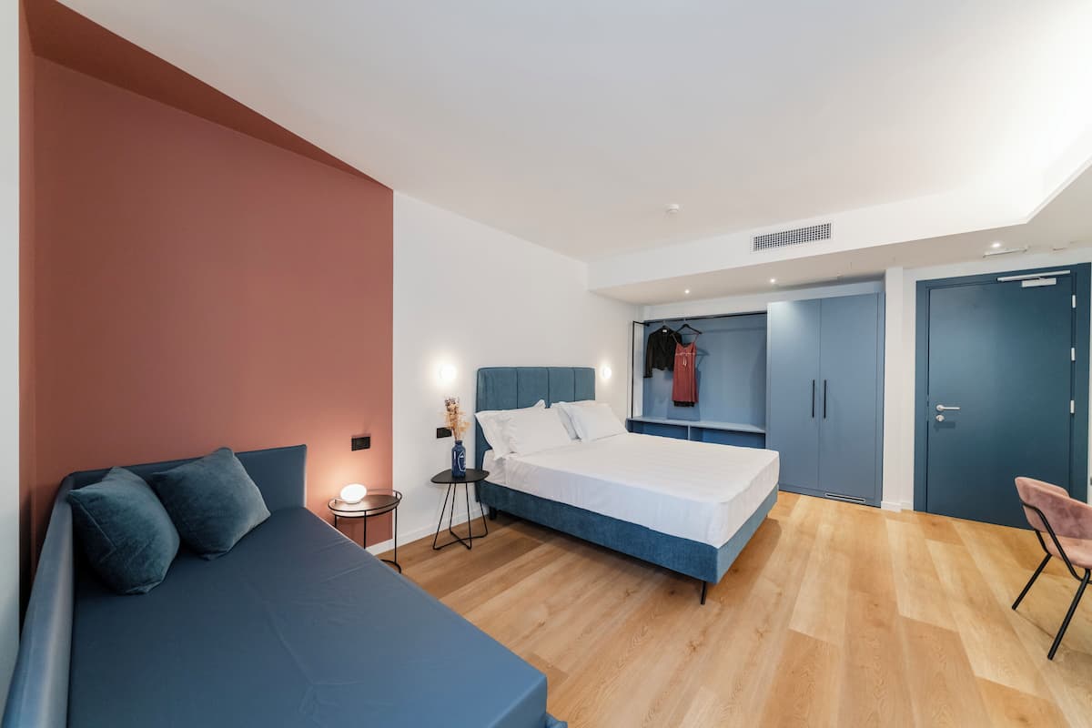 Quarto moderno com cama grande, mesa de cabeceira, cadeira e guarda-roupa.