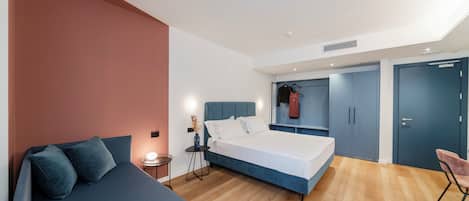 A modern bedroom with a large bed, a bedside table, a chair, and a wardrobe.