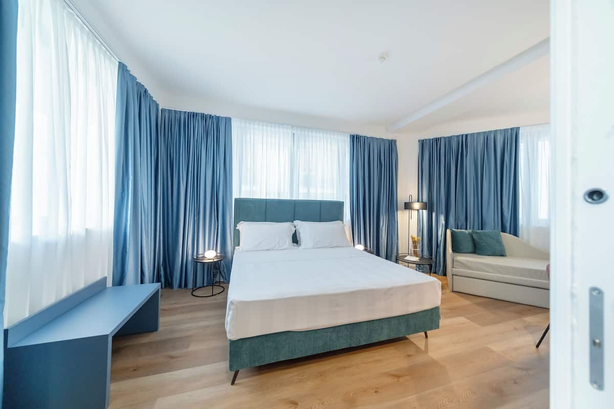 Quarto de hotel moderno com uma cama grande, um sofá e uma escrivaninha.