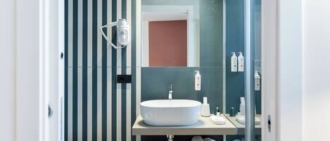 Un baño moderno con un lavamanos grande de color blanco, un espejo y una cabina de ducha de vidrio.