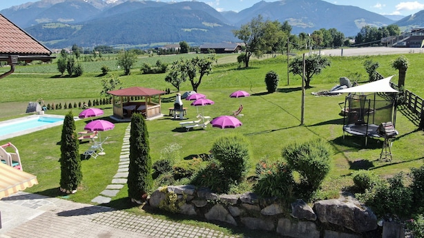 A lush garden with a pool, outdoor seating, and a playground. - Residence Garni Untermoahof (Brunico)