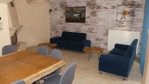 Un comedor con una mesa y sillas de madera, un sofá azul y una pared de ladrillo rústico.