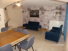 Un comedor con una mesa y sillas de madera, un sofá azul y una pared de ladrillo rústico.