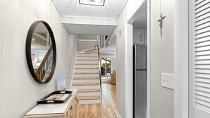 A hallway with a wooden staircase, a white wall, and a refrigerator. - Gorgeous Oceanfront Villa, w/ Pool on Hilton Head (Hilton Head Island)