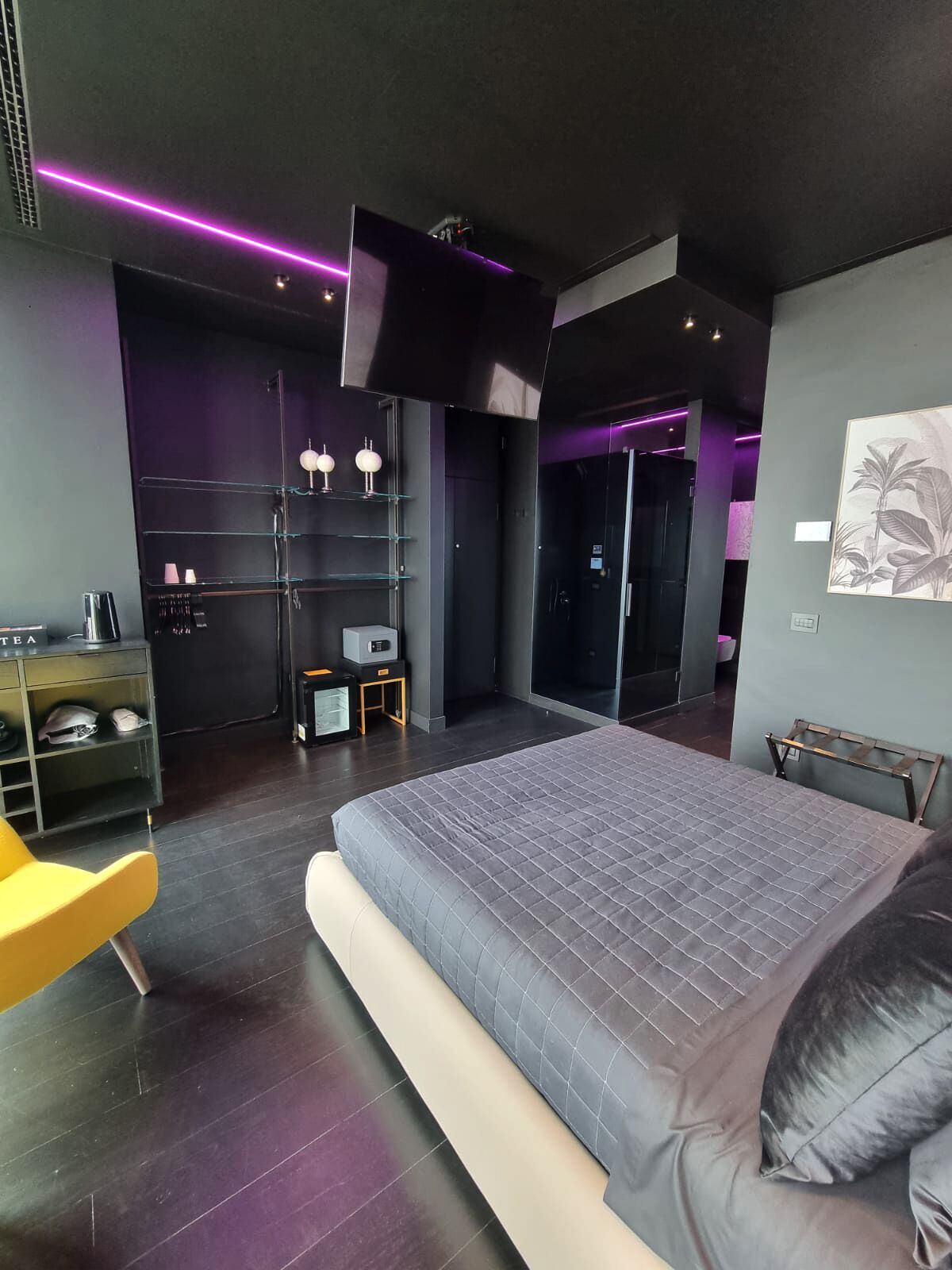 A modern bedroom with a large bed, a small desk, a chair, and a wardrobe.