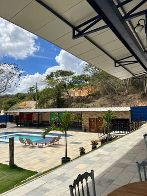 A covered outdoor area with a swimming pool, lounge chairs, and a patio with tables and chairs. - Lago São Franscisco Parque Hotel (Garanhuns)