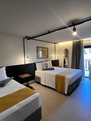 Habitación de hotel con dos camas, una mesita de noche, una pequeña mesa, un cuadro en la pared y vistas al exterior.