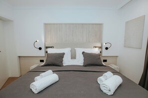 A hotel room with a large bed, two bedside tables, a headboard, and wall-mounted lamps. - Central Deluxe Apartment with Workspace - Apartment Datala (Marina)
