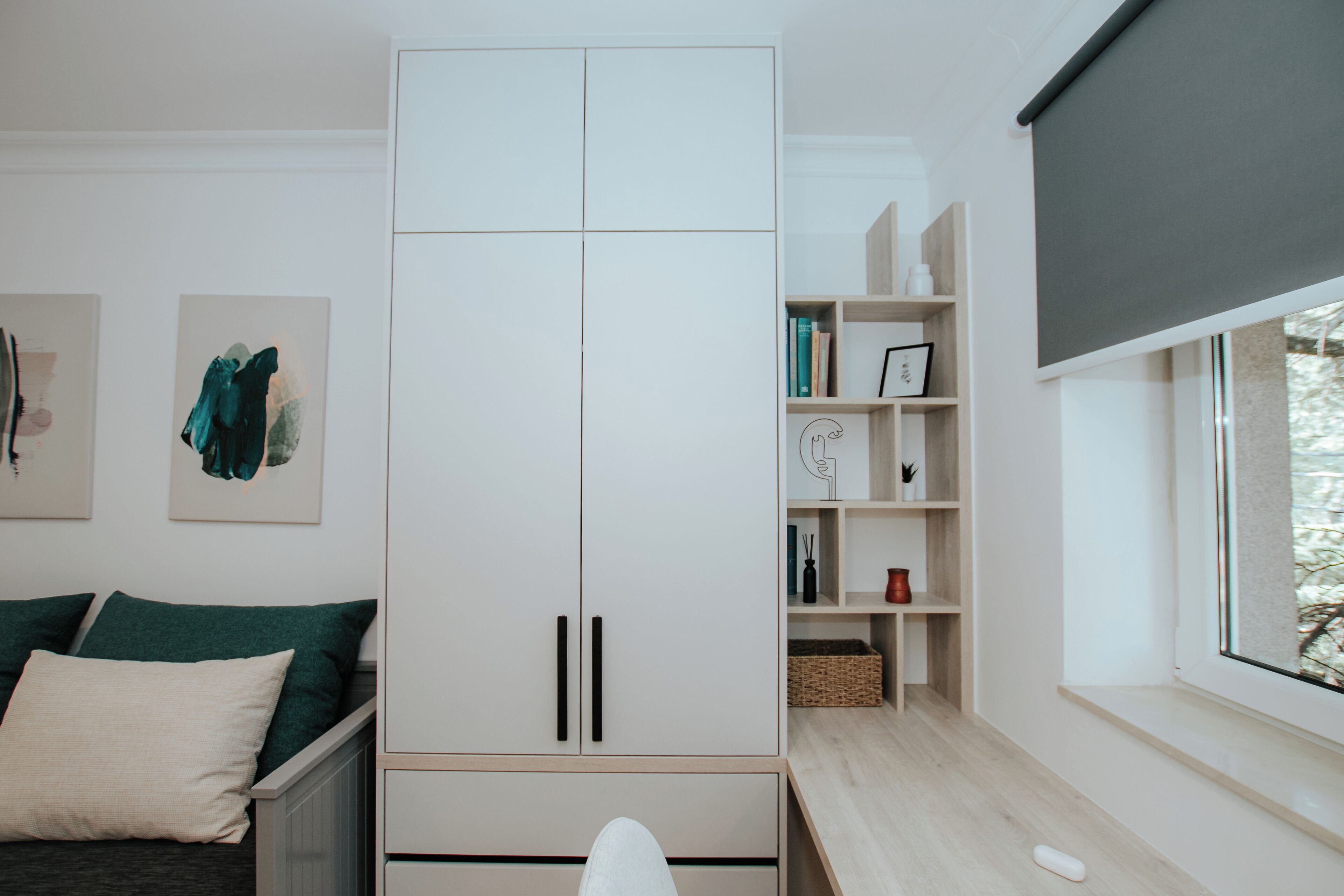 Une chambre à coucher moderne, équipée d’un lit, d’une armoire, d’un bureau et d’une fenêtre donnant sur un beau paysage.