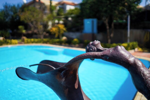 A close-up of a bronze sculpture by a swimming pool.