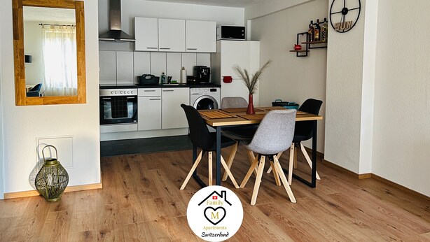 Een moderne keuken met witte kasten, een eettafel met stoelen en een spiegel.