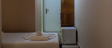 Habitación de hotel con dos camas, un armario de madera y un refrigerador pequeño.