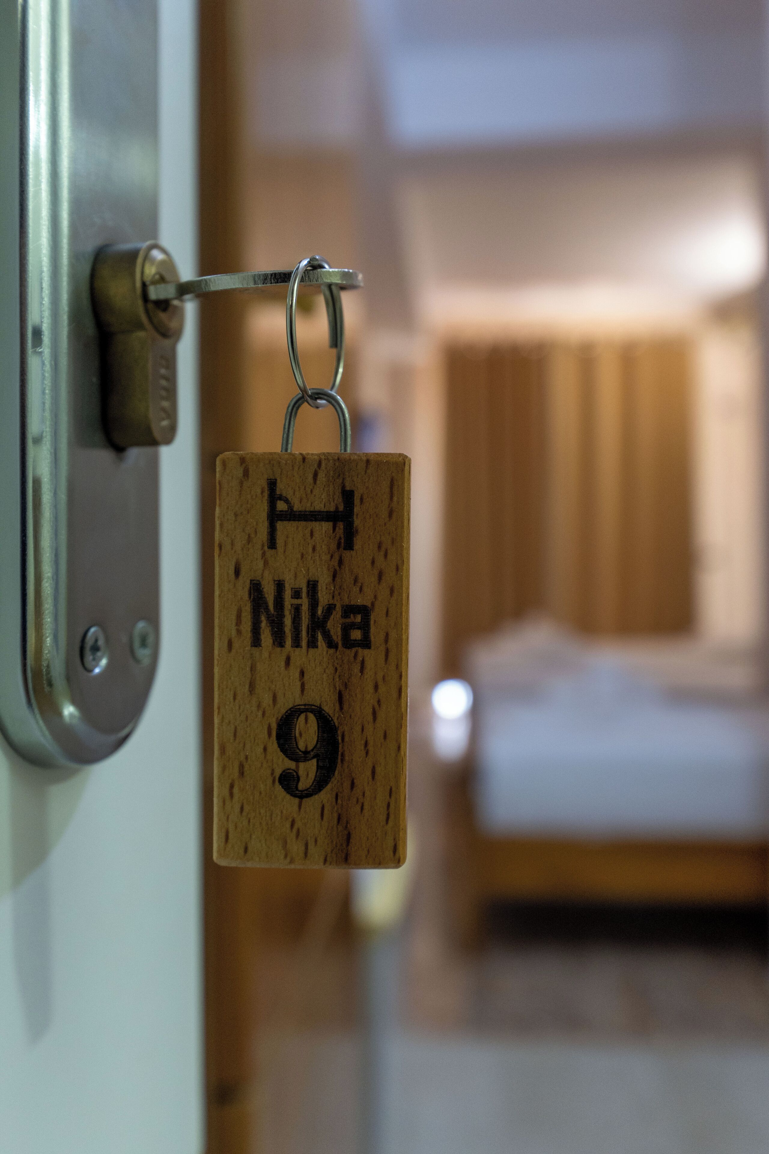 Un porte-clés en bois avec la mention « Nika 9 » gravée, suspendu à une serrure métallique.