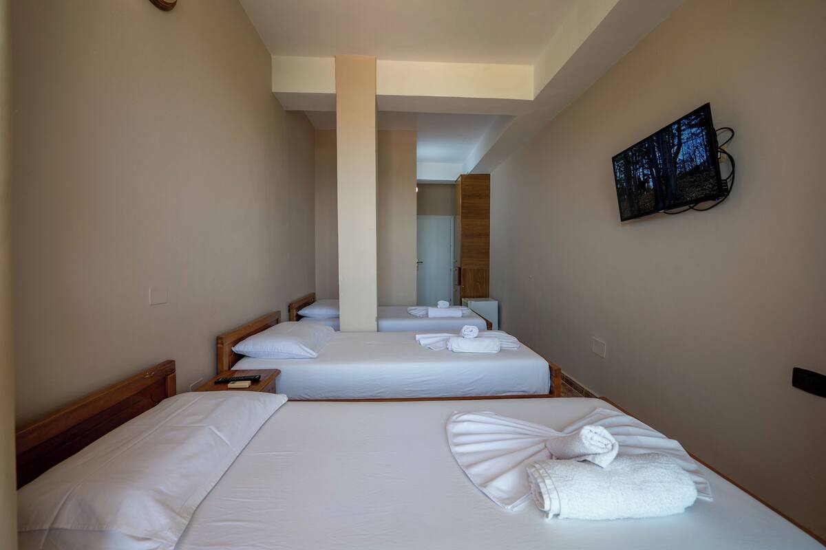 A hotel room with two beds, a TV mounted on the wall, and a wooden headboard.