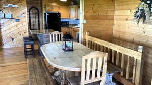 A wooden cabin interior with a dining area featuring a large wooden table, benches, and a black lantern. - Breathtaking Views!  Spacious Cabin, HotTub, pool table near PF & Gatlinburg ⛰️ (Sevierville)