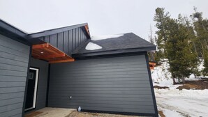 Una casa moderna con fachada gris oscuro, una puerta visible y un pequeño porche.