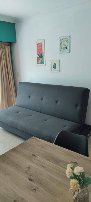 A grey sofa with a wooden coffee table in front. There are two framed pictures on the wall. - Beautiful And Comfortable Near To Subway (Buenos Aires)