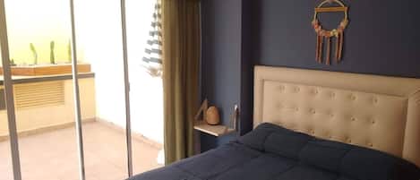 Une chambre dotée d’un grand lit, d’une porte-fenêtre coulissante donnant sur un balcon et d’un élément décoratif fixé au mur.
