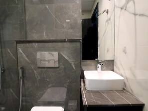 Ein modernes Badezimmer mit einem rechteckigen Waschbecken, einer Duschbrause und einem Spiegel an der Wand.