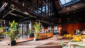 A spacious indoor area with a bar, seating, and large windows. - Noxx Hotel (Marburg)