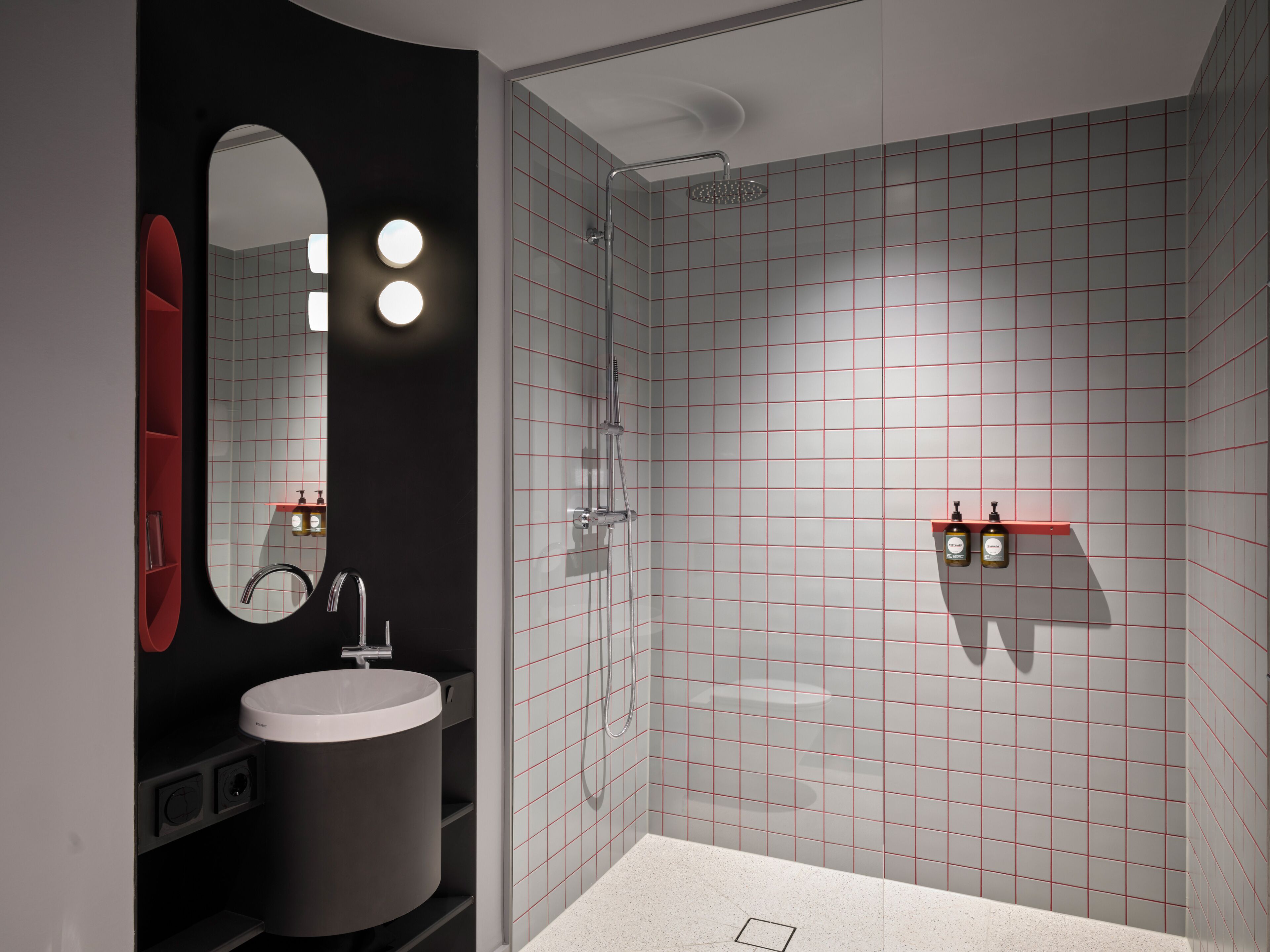A modern bathroom with a round mirror, a sink, and a shower.