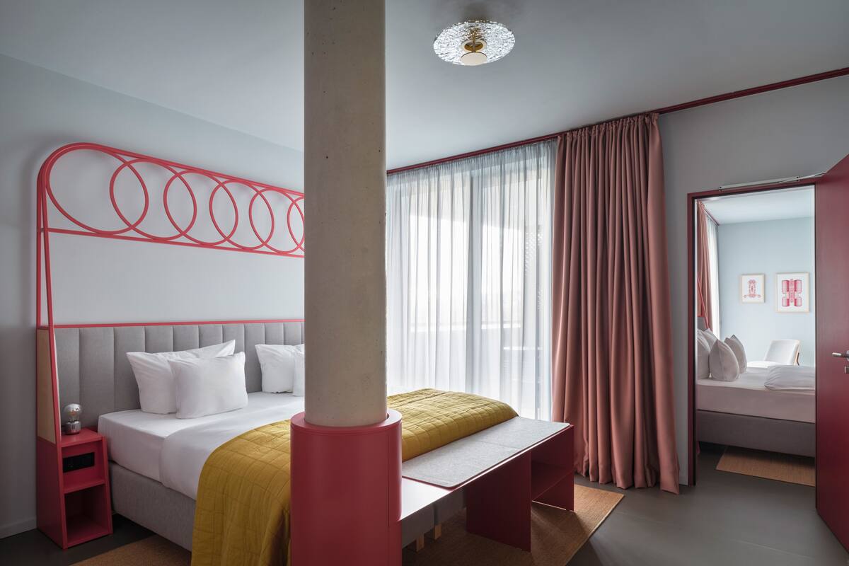 Ein modernes Hotelzimmer mit Bett, Nachttisch und einem großen Spiegel.