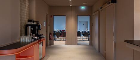 A hotel corridor with a reception desk, a fire extinguisher, and an exit door.