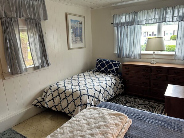 A bedroom with a bed, a dresser, a window with curtains, and a framed picture on the wall. - Family Cottage Big yard w\Fire Pit & Outside Shower Walk to beaches Pets👍🏻Sat-Sat (Yarmouth)