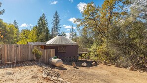 A rustic cabin with a metal roof, surrounded by a wooden fence and a dirt path. - Unique authentic yurt stay near Yosemite National Park  (Wishon)