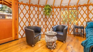A cozy interior with a wooden floor, two leather chairs, a round table with a decorative item, and a hanging plant. - Unique authentic yurt stay near Yosemite National Park  (Wishon)