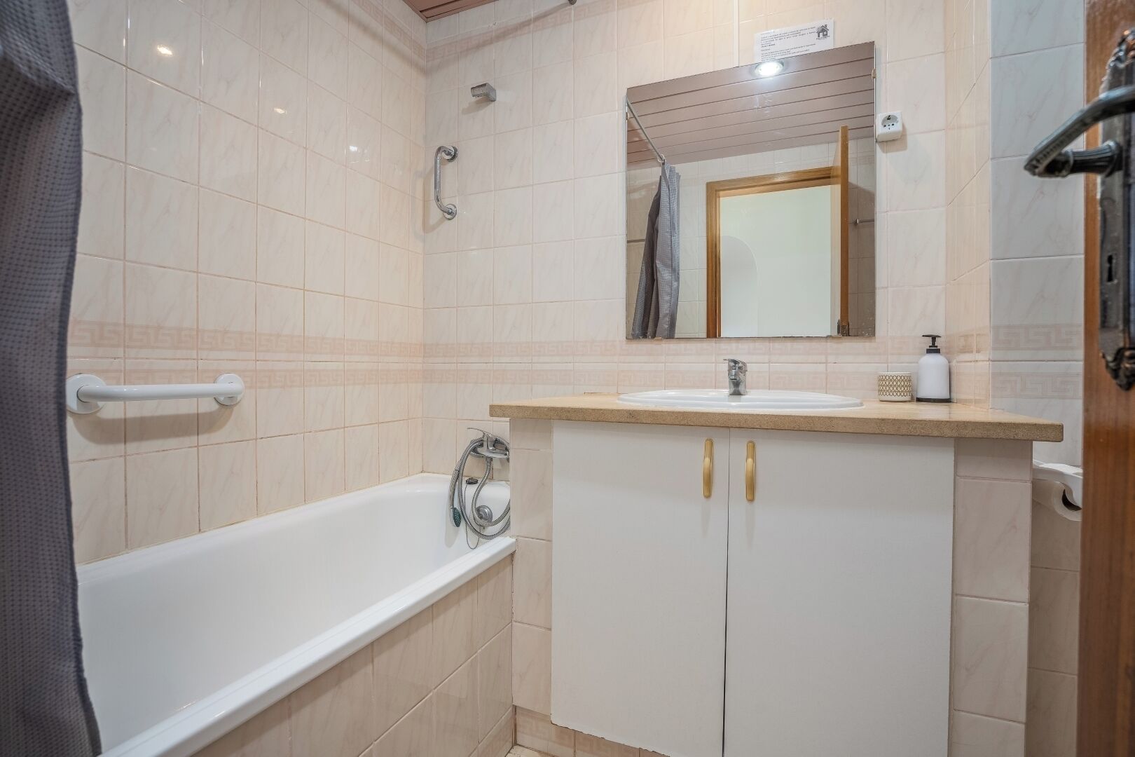 Un baño con bañera, lavabo con espejo y ducha.