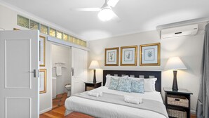A neatly arranged bedroom with a bed, bedside tables, a nightstand, a bench, and a ceiling fan.