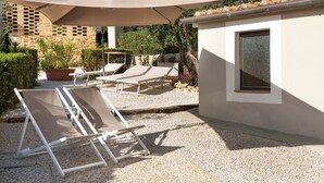 A patio with two lounge chairs and a large umbrella, a small building with a window, and a gravel ground. - "A CASA DI FRANCA" PRIVATE VILLA IN CHIANTI
A RURAL REFUGE FOR FAMILIES (Gambassi Terme)
