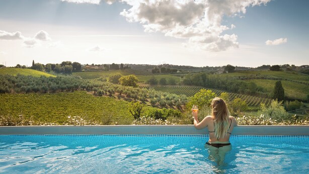 A person in a swimming pool with a view of green fields and a clear sky. - "A CASA DI FRANCA" PRIVATE VILLA IN CHIANTI
A RURAL REFUGE FOR FAMILIES (Gambassi Terme)
