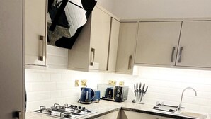 A modern kitchen with white cabinets, a gas stove, a coffee maker, and a sink.