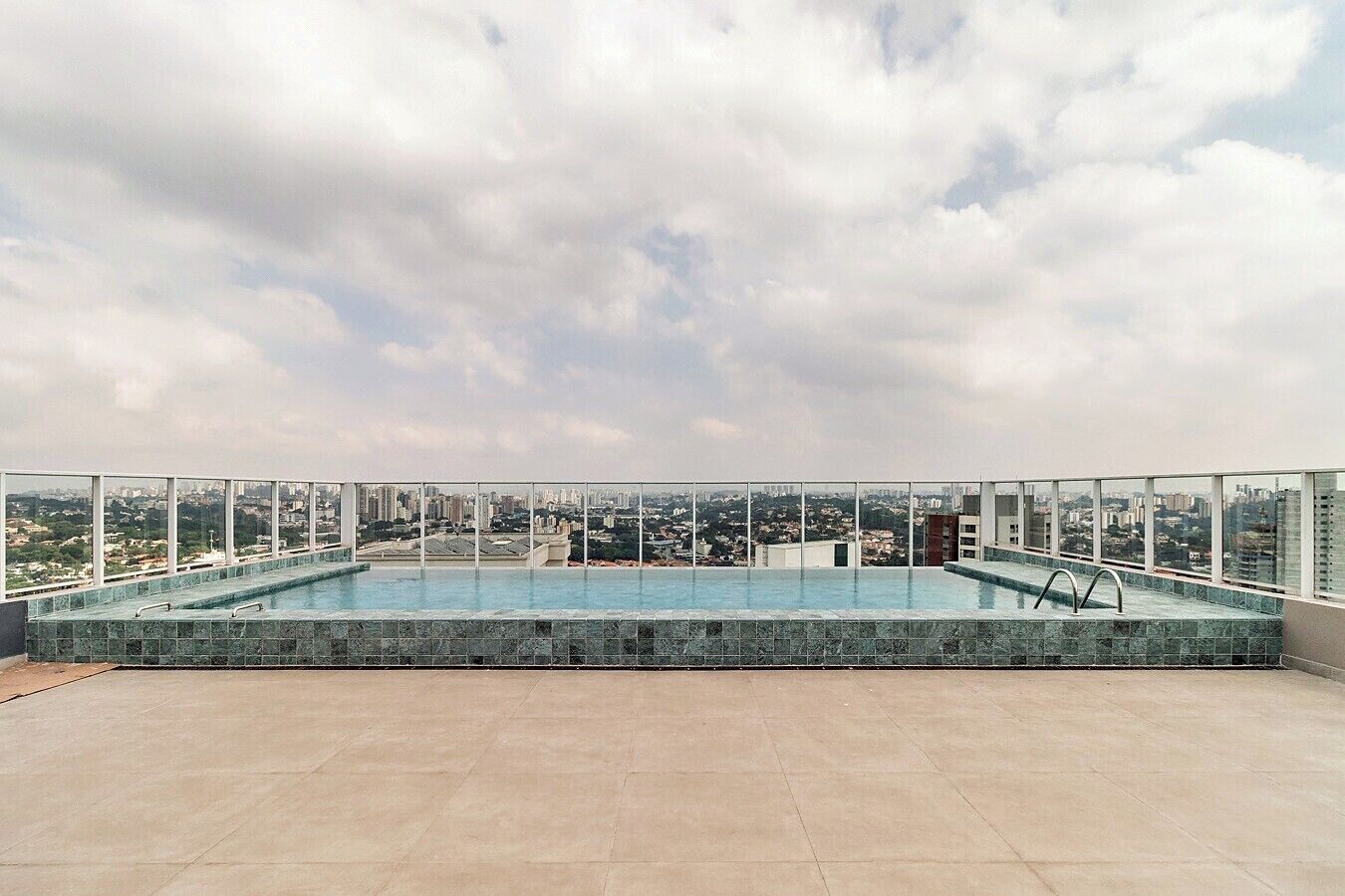 A rooftop infinity pool with a city view, surrounded by a glass railing.