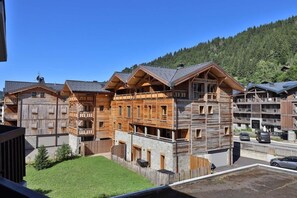 Un immeuble en bois à plusieurs étages, doté de balcons, entouré d’une zone délimitée par une clôture et d’un parking.