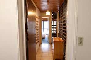 Un pasillo estrecho con una puerta de madera, un banco de madera y una pared con diseño de cuadrícula.