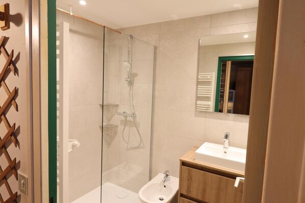 Une salle de bain moderne avec une douche à parois de verre, un meuble-lavabo en bois et un miroir.