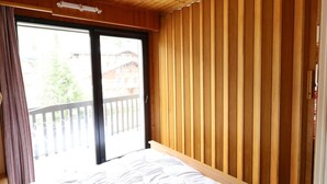 Ein Schlafzimmer mit Holzboden, einem großen Fenster und einem Balkon.