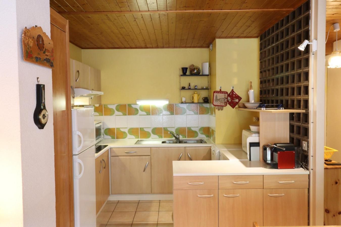 Cocina compacta con armarios de madera, horno empotrado y salpicadero de azulejos.
