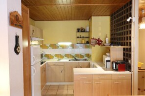A compact kitchen with wooden cabinets, a built-in oven, and a tiled backsplash.