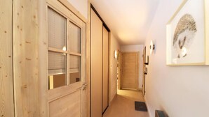 A hallway with wooden doors, a framed picture on the wall, and a vent on the floor.