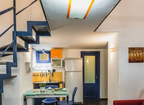 A compact kitchen with a refrigerator, a sink, and a dining area with a table and chairs. - Catania City Apartment by Wonderful Italy (Catania)