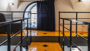 A narrow staircase with a metal railing, leading to a room with a window and a door. - Catania City Apartment by Wonderful Italy (Catania)
