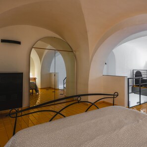 A bedroom with a bed, a TV, and a large arched mirror reflecting the room. - Catania City Apartment by Wonderful Italy (Catania)