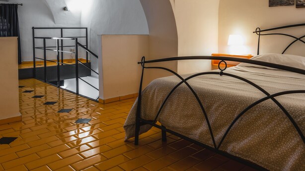 A bedroom with a bed, a staircase, and a view of the outdoors. - Catania City Apartment by Wonderful Italy (Catania)