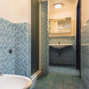 A bathroom with a tiled floor, a sink, a mirror, and a shower. - Catania City Apartment by Wonderful Italy (Catania)