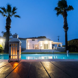 Una casa moderna con piscina, una linterna y palmeras.